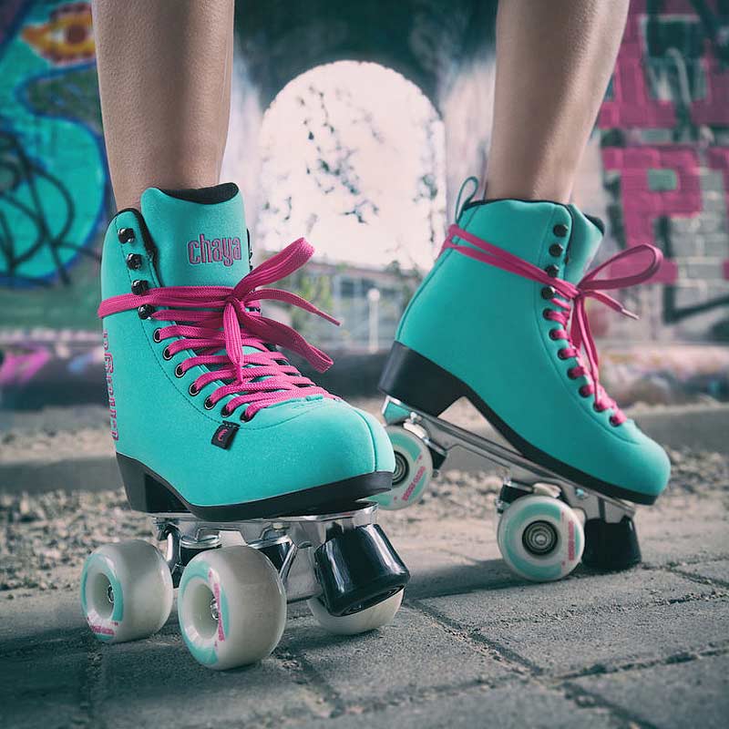 Teal roller skates with pink laces on a blurred street background