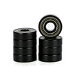 Four black metal bearings in two stacks with one bearing standing upright to show its inner race and outer ring details, set against a plain white background.