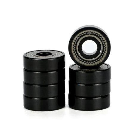 Four black metal bearings in two stacks with one bearing standing upright to show its inner race and outer ring details, set against a plain white background.