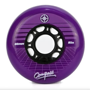 A single purple inline skate wheel with a black hub, featuring the brand name 'Compass' and size markings '80mm' and '85A' on a clean white background.