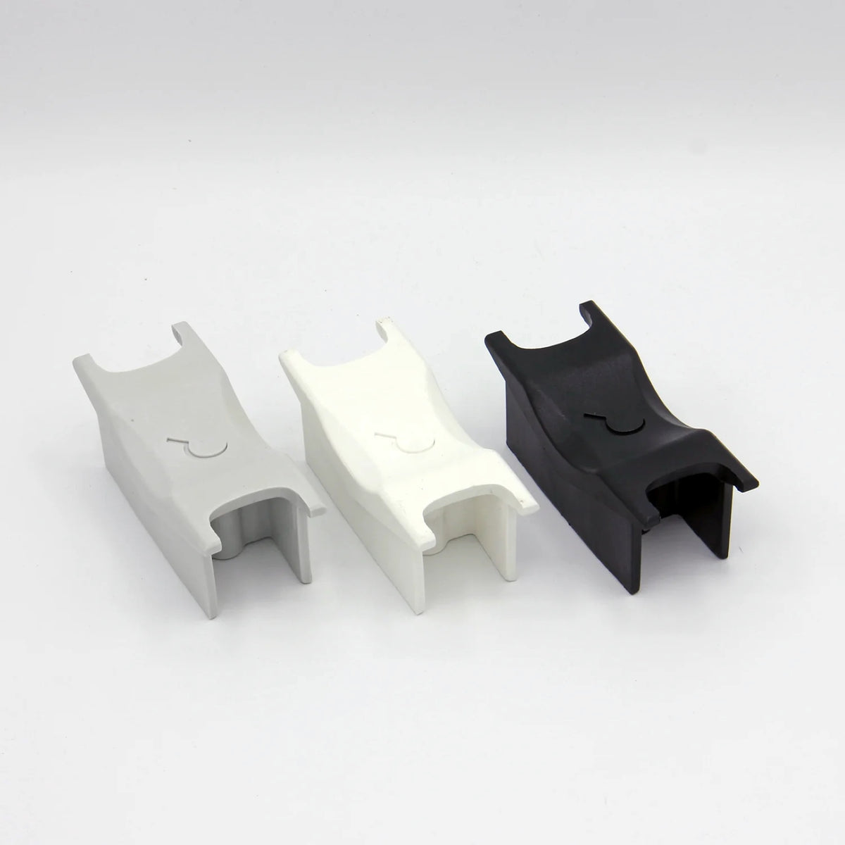 3 aggressive inline skate frame 'H-block' parts in grey, white and black lined up next to each other on a white background.