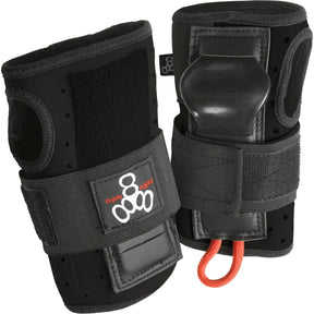 Two black wrist guard pads next to each other standing upright against a white background. The pads feature velcro straps with a brand logo on it, thumb holes, and a rigid plastic piece protruding out where your palm would be.  There is also a small orange loop of cord attached to the bottom. 